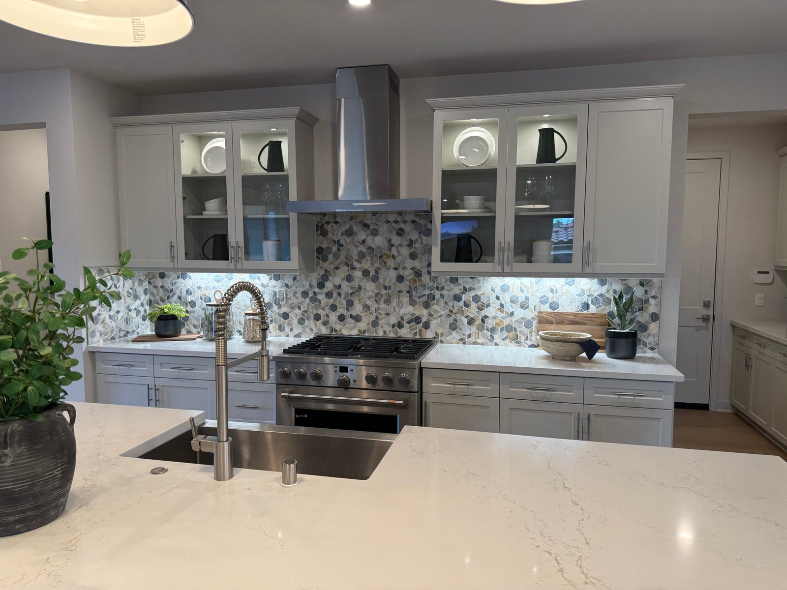 Beautiful new kitchen with a deep farmhouse sink in island and industrial style faucet with white quartz countertop. Mosaic tile backsplash. Glass upper cabinet doors. Stainless appliances. Poway Rancho Bernardo Scripps Ranch