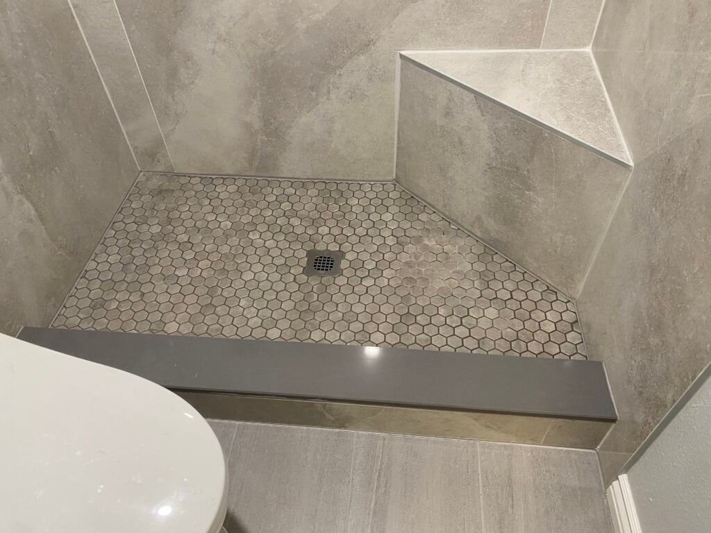 New walk in shower with seat and threshold. Beautiful tile flooring and large format tile on the walls